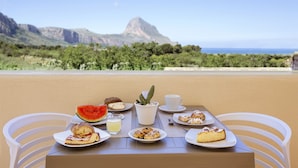 A table set with food and a cactus on a balcony with a mountain view. - Cala di Ponente (San Vito Lo Capo)