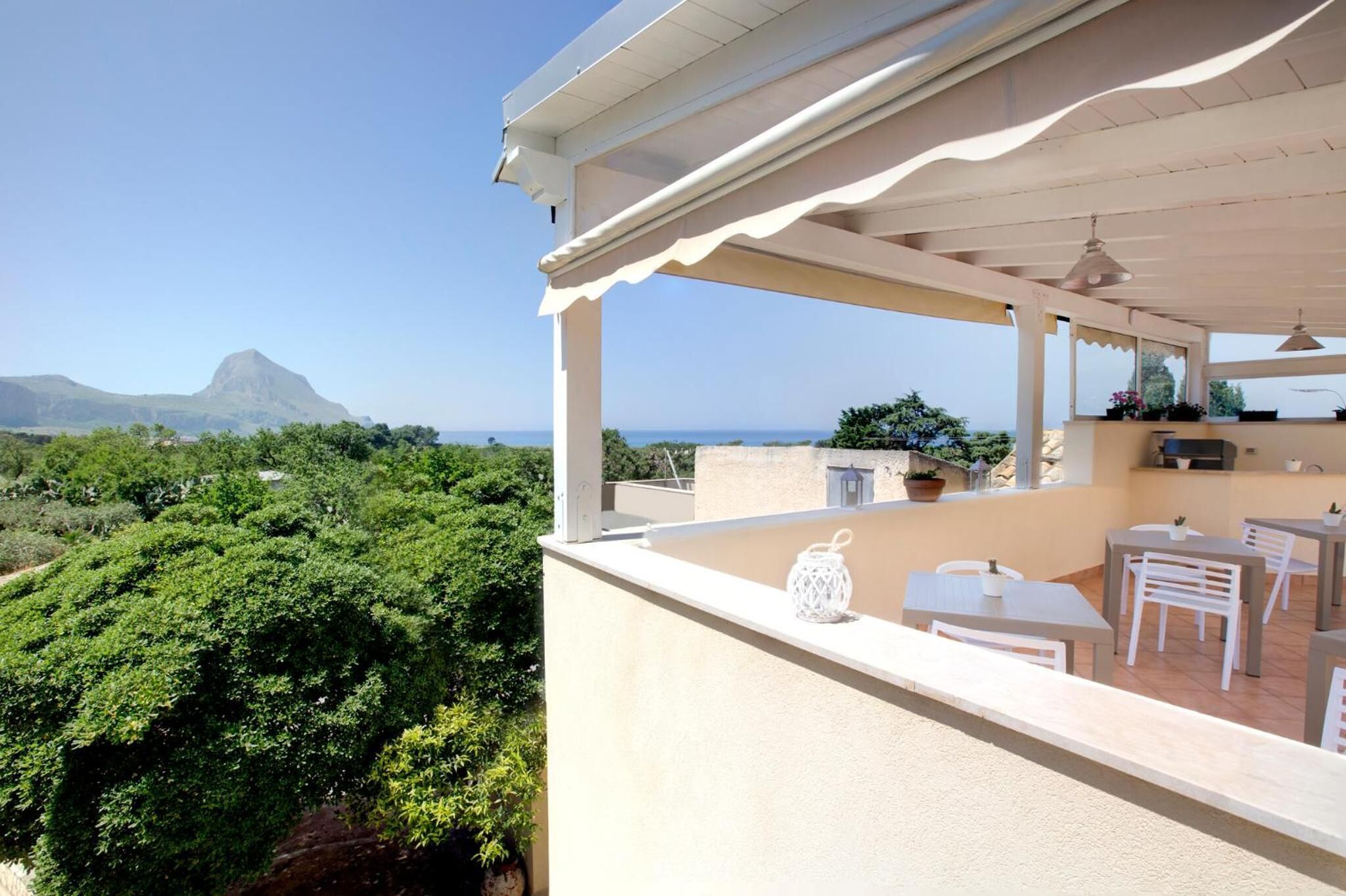 Un balcón con mobiliario exterior, vistas a la montaña y una zona de patio con una parrilla.