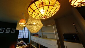 A room with three hanging lamps with a woven design, a white cabinet with shelves, and a window with a grid pattern. - Swiss Inn (Sapporo)