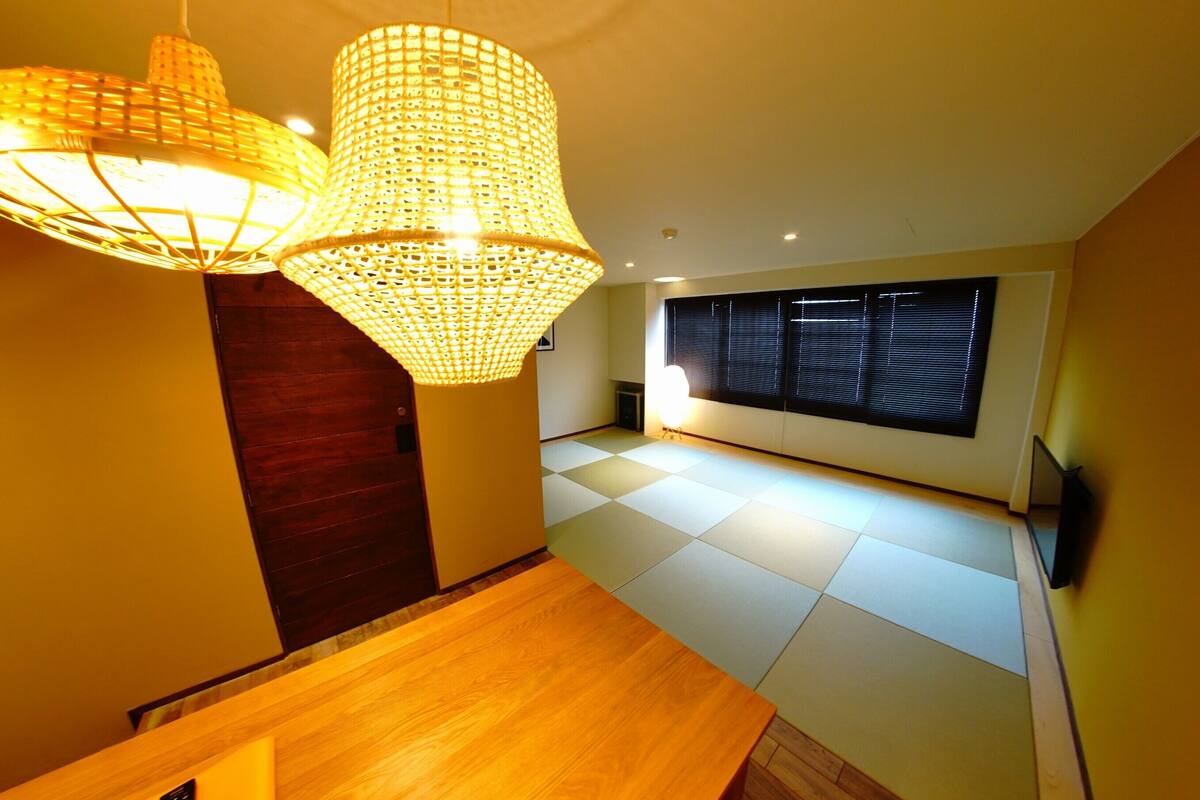 Un intérieur moderne avec un plancher en bois, une porte sombre et une grande fenêtre équipée de stores.
