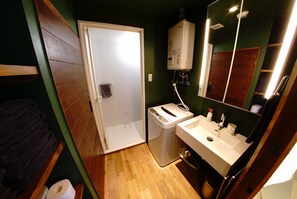 Un bany petit i funcional amb un lavabo blanc, un mirall, un escurapous i un radiador.