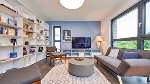 Ein modernes Wohnzimmer mit einer Couch, einem Sessel, einem Couchtisch und einem Bücherregal voller Bücher und Dekoration.
