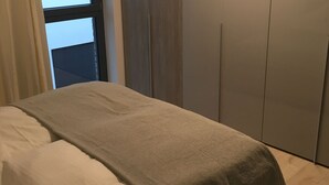 Ein Schlafzimmer mit Bett, Fenster und Kleiderschrank.