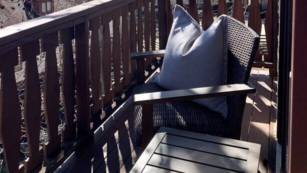 Une terrasse en bois avec un banc et des coussins, offrant une vue sur un paysage montagneux.