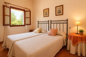 A room with two beds, a window with curtains, a bedside table with a lamp, and two framed pictures on the wall. - Charming House - 6 pax, - Wifi Free - Sat TV - Private Salat Pool (Manacor)