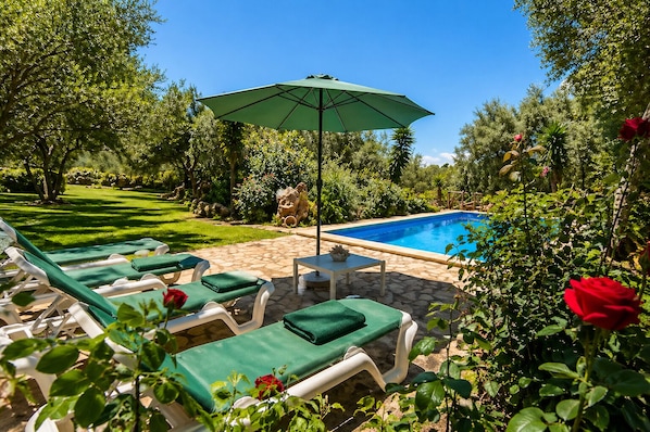 A pool area with lounge chairs and an umbrella.