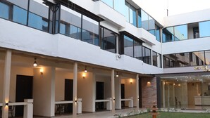 Un hotel moderno con varios pisos, zonas de estar al aire libre y un pequeño jardín.