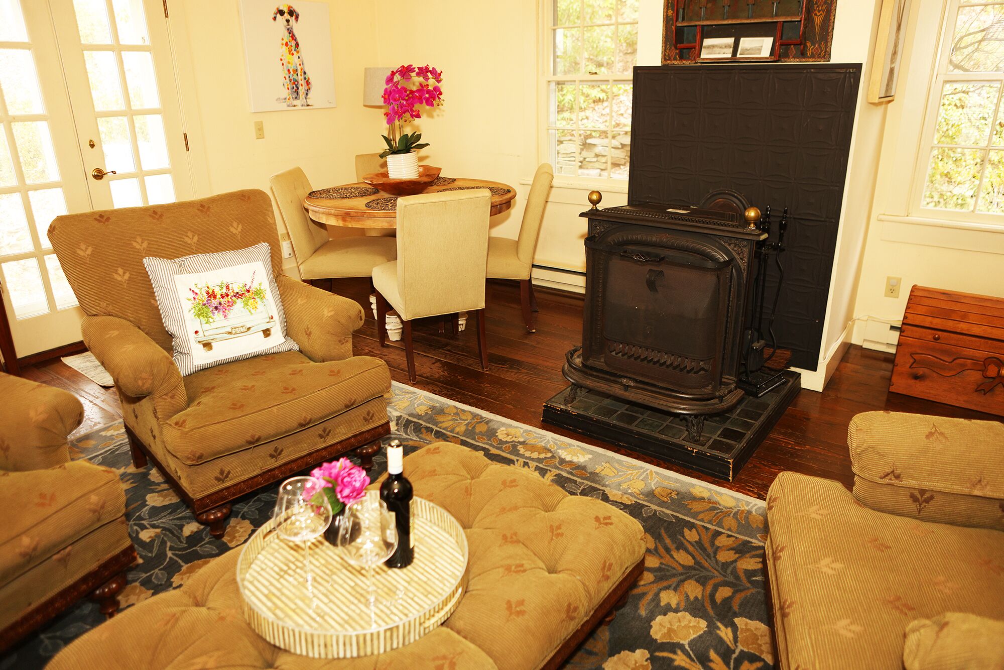 A cozy living room with a vintage wood-burning stove, comfortable seating, and a dining area with a table and chairs.