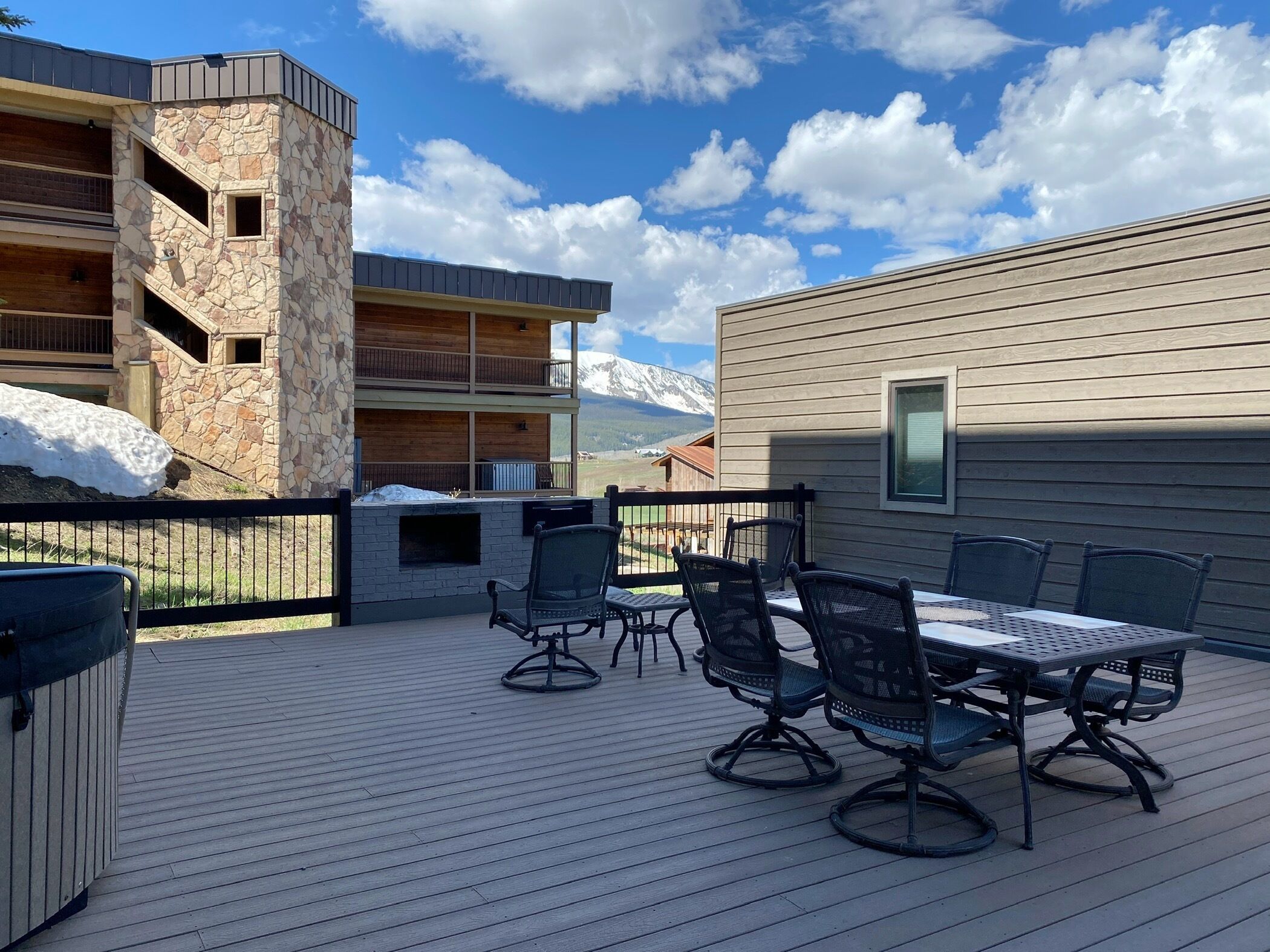 Une terrasse en bois avec des meubles d’extérieur, un mur en pierre et une vue sur les montagnes.