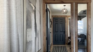 Een modern interieur met een grijze bank, een houten deur en een zwarte deur op de achtergrond.
