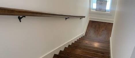 A wooden staircase with white walls and a window at the top.