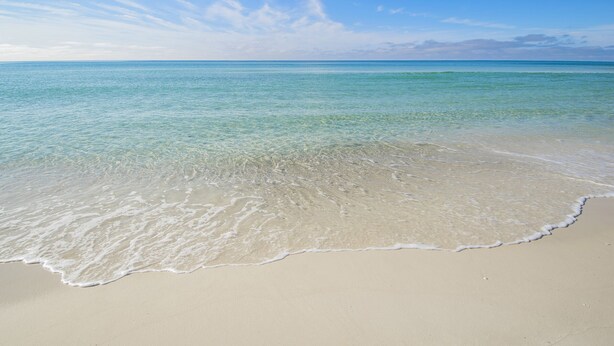 Una playa con agua turquesa cristalina y una orilla arenosa.