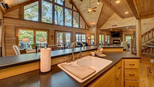 A spacious kitchen with a large island, wooden cabinetry, and a stone fireplace. - Lodge On The Lake- Pet Friendly | Waterfront w/ Dock | Beautiful Views (Blue Ridge)