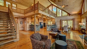 A spacious log cabin with a wooden interior, a staircase to a loft, and a dining area. - Lodge On The Lake- Pet Friendly | Waterfront w/ Dock | Beautiful Views (Blue Ridge)