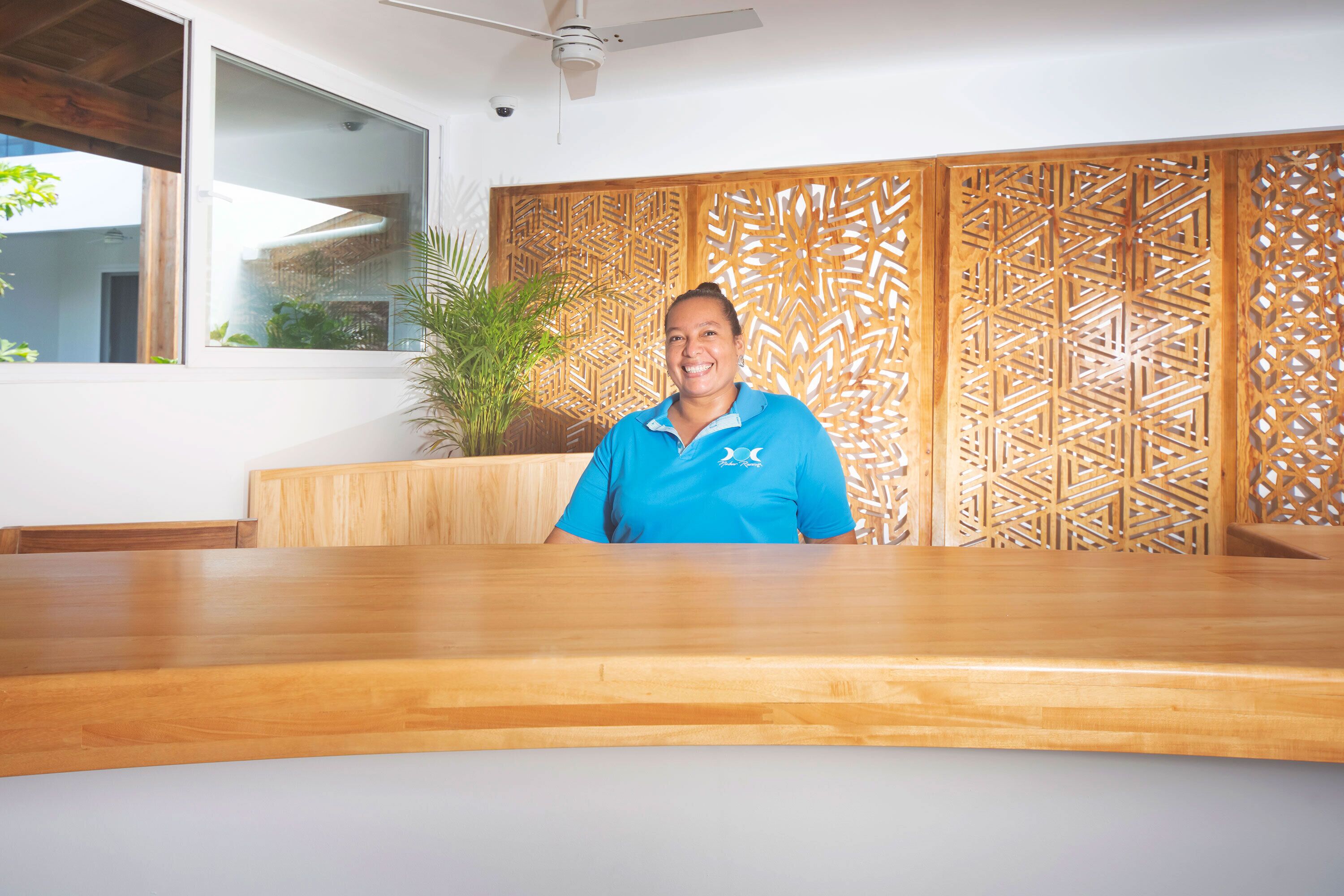 A reception area with a wooden reception desk, a large window, and a decorative wooden panel wall.