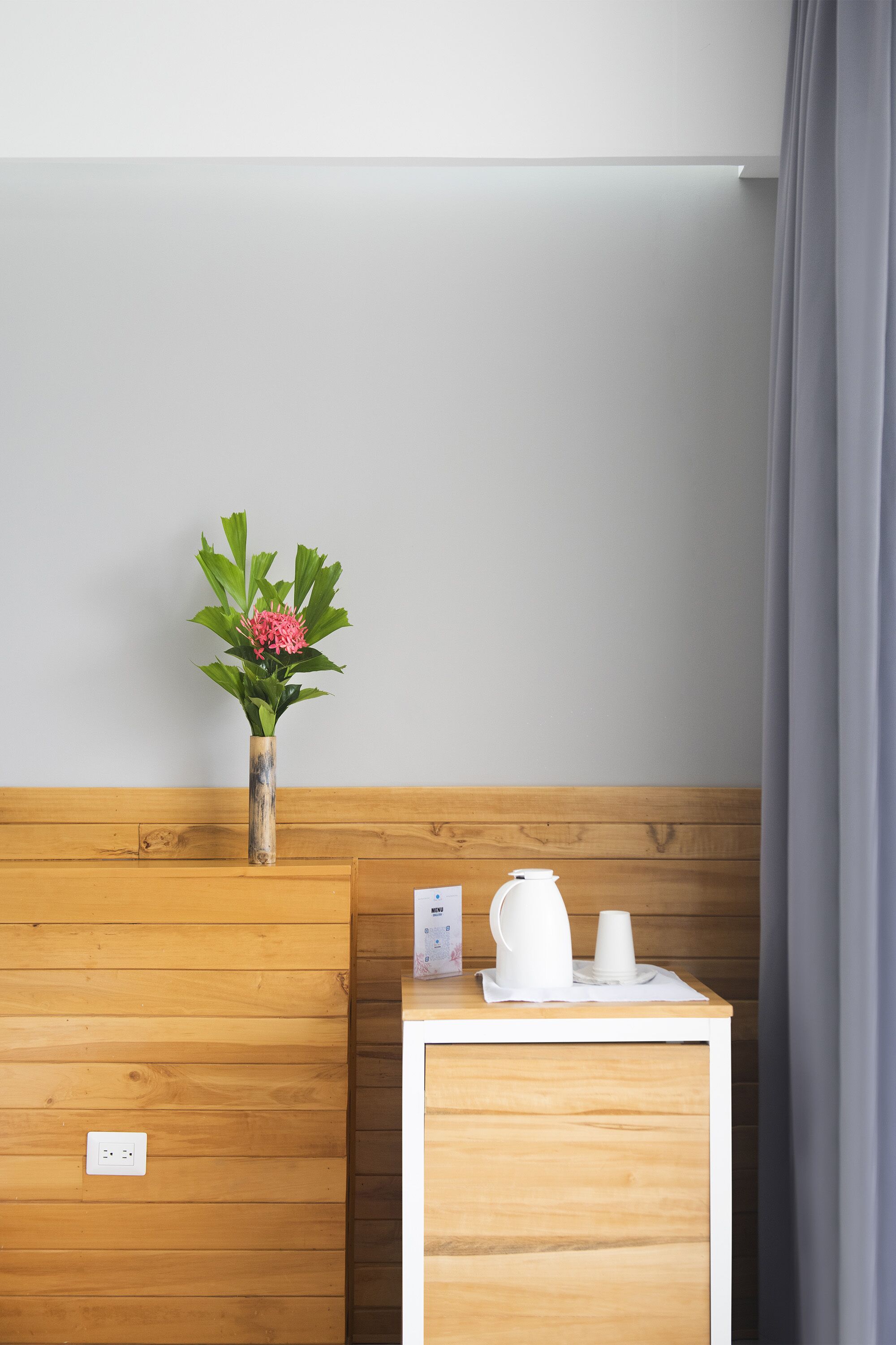 A wooden bench with a vase of flowers and a small table with a kettle and cups.