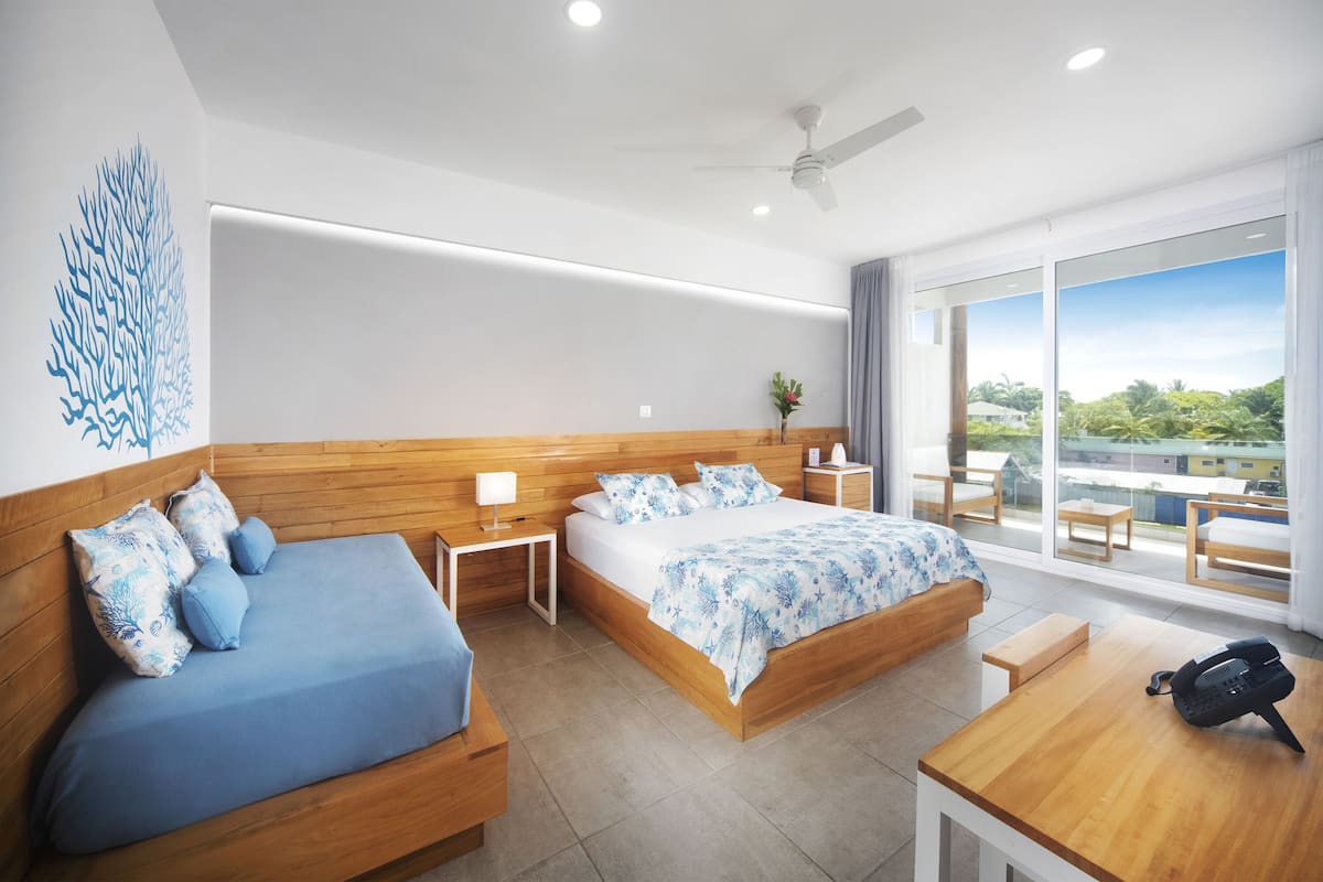 A modern hotel room with two beds, a wooden headboard, a large window with a view, and a small table with a telephone.