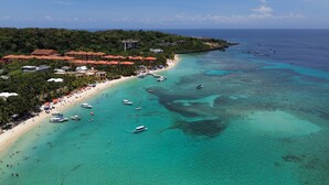 Un resort costero con playa, barcos y zona boscosa.