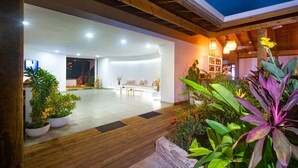 Un espacio interior amplio con piso de madera, paredes blancas y una zona de estar con sofá y mesa de centro.