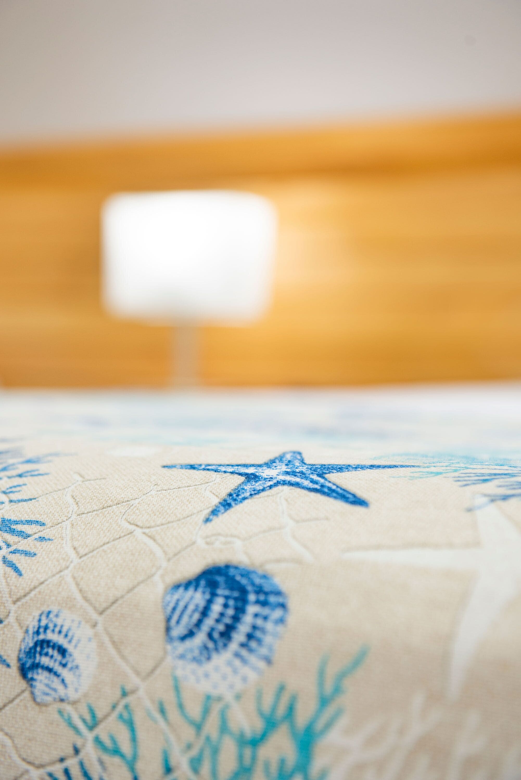 A close-up of a bed with a blue starfish and seashell pattern.