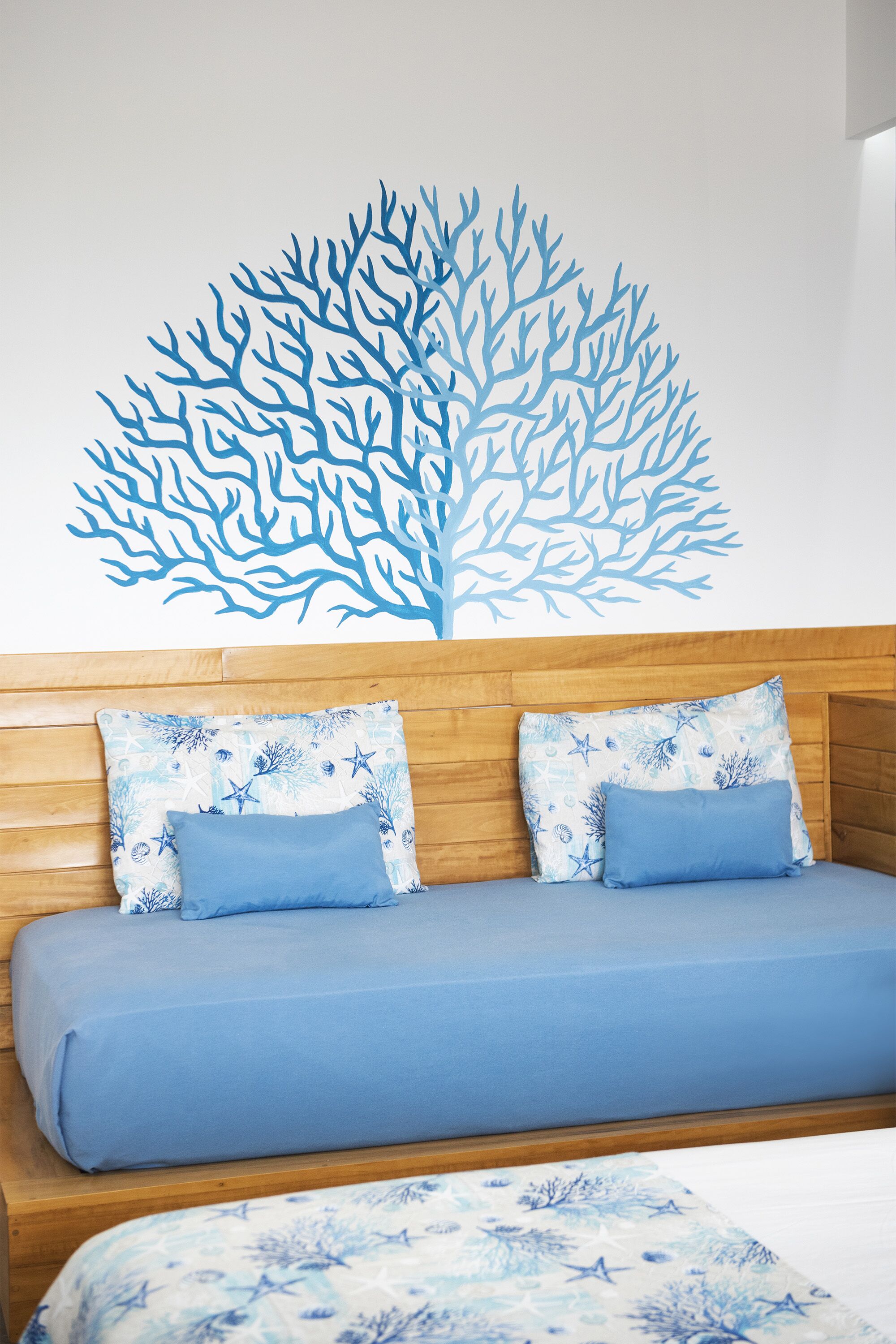 A bedroom with a wooden headboard, a blue bedspread, and matching pillows.