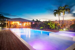 Una piscina al aire libre, sombrillas, sillones reclinables de piscina