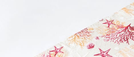 A bed with a white bedspread and pillows featuring a coral reef pattern.