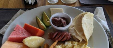 A breakfast plate with eggs, toast, fruit, and potatoes.