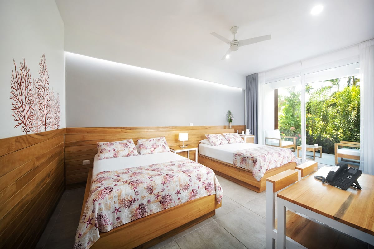A hotel room with two beds, a desk, and a phone.