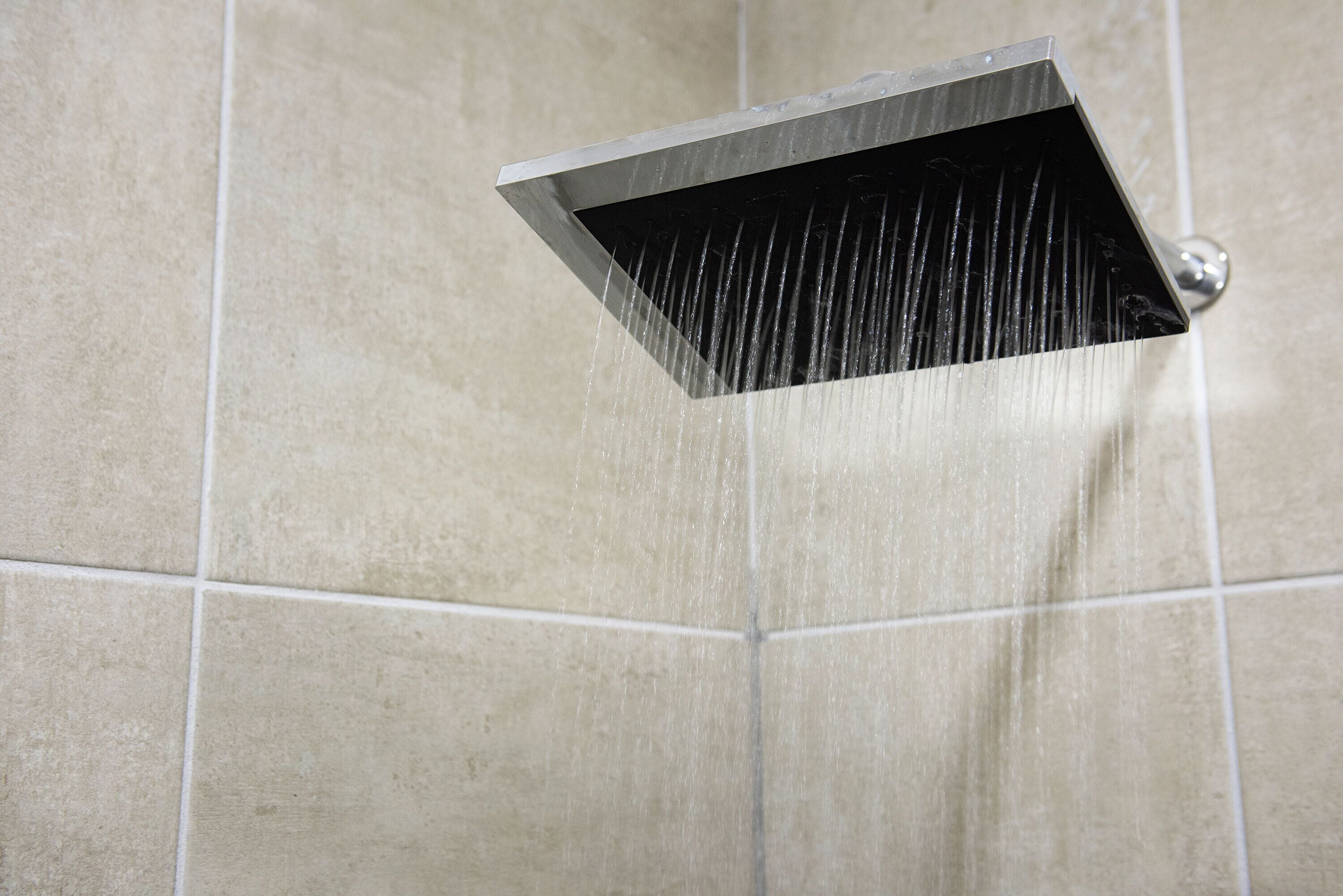 A showerhead in a tiled bathroom.