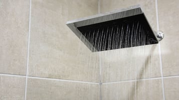 A showerhead in a tiled bathroom.