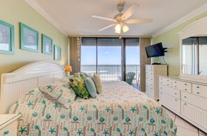 Une chambre avec un lit, une télévision, une commode et un balcon donnant sur la plage.