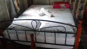 A bed with a metal frame and wooden headboard, a floral bedspread, and a red pillow.