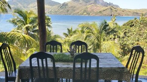 A table set outdoors with a view of the sea and hills.