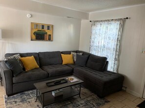 A living room with a sectional sofa, a coffee table, and a patterned rug.