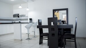 A modern kitchen with white cabinets, a black dining table, and two black chairs. - La Estancia Apartments Mazatlan 2 (Mazatlán)