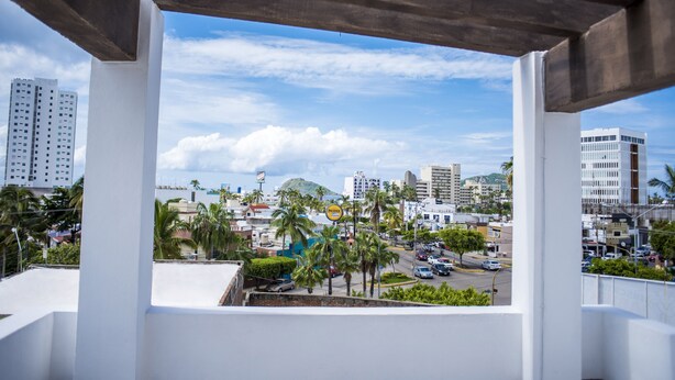 A view from a balcony with a clear sky, palm trees, and urban buildings. - La Estancia Apartments Mazatlan 2 (Mazatlán)
