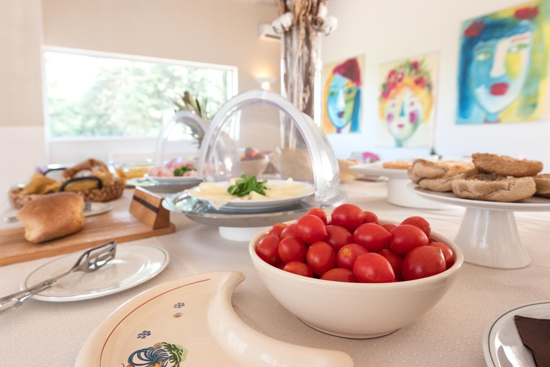 Una mesa de buffet con diversos alimentos, incluyendo un tazón de tomates cherry, pan y otros platos.