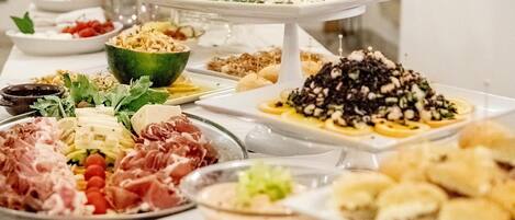 A buffet table with various food items including meats, cheeses, and salads.
