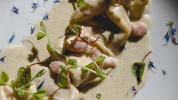 En tallrik med ravioli i en krämig sås, garnerad med små groddar.