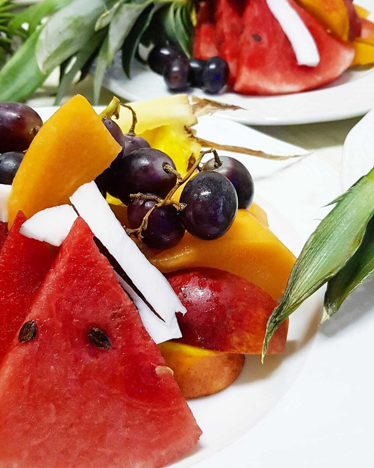 Un plato con una variedad de frutas, como sandía, uvas y tajadas de mango.