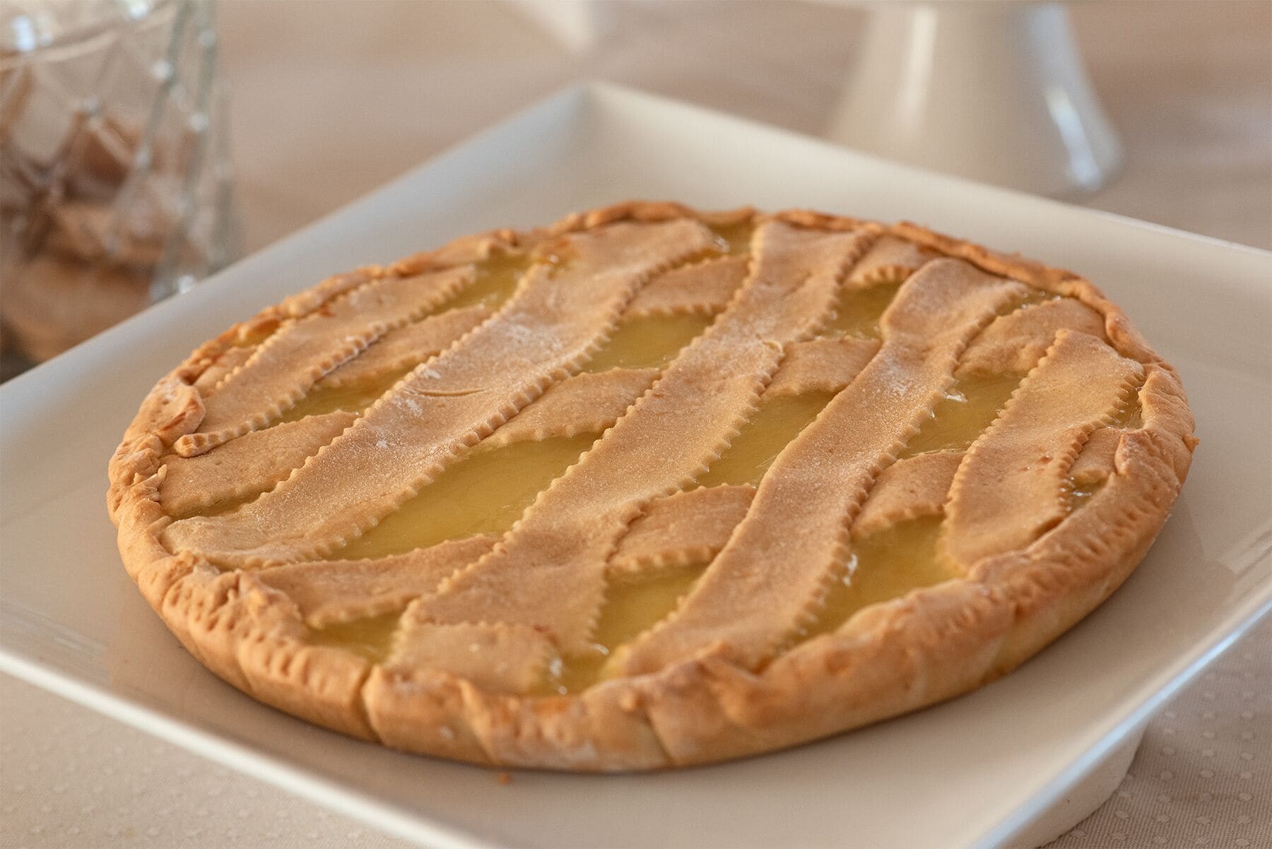 Una tarta redonda con una cubierta enrejada sobre un plato blanco.