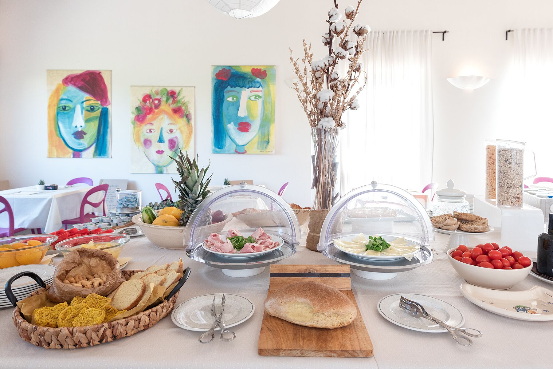 Un buffet de petit-déjeuner proposant une variété d’aliments, notamment des fruits, de la viande et des viennoiseries, disposés sur une table recouverte d’une nappe blanche.