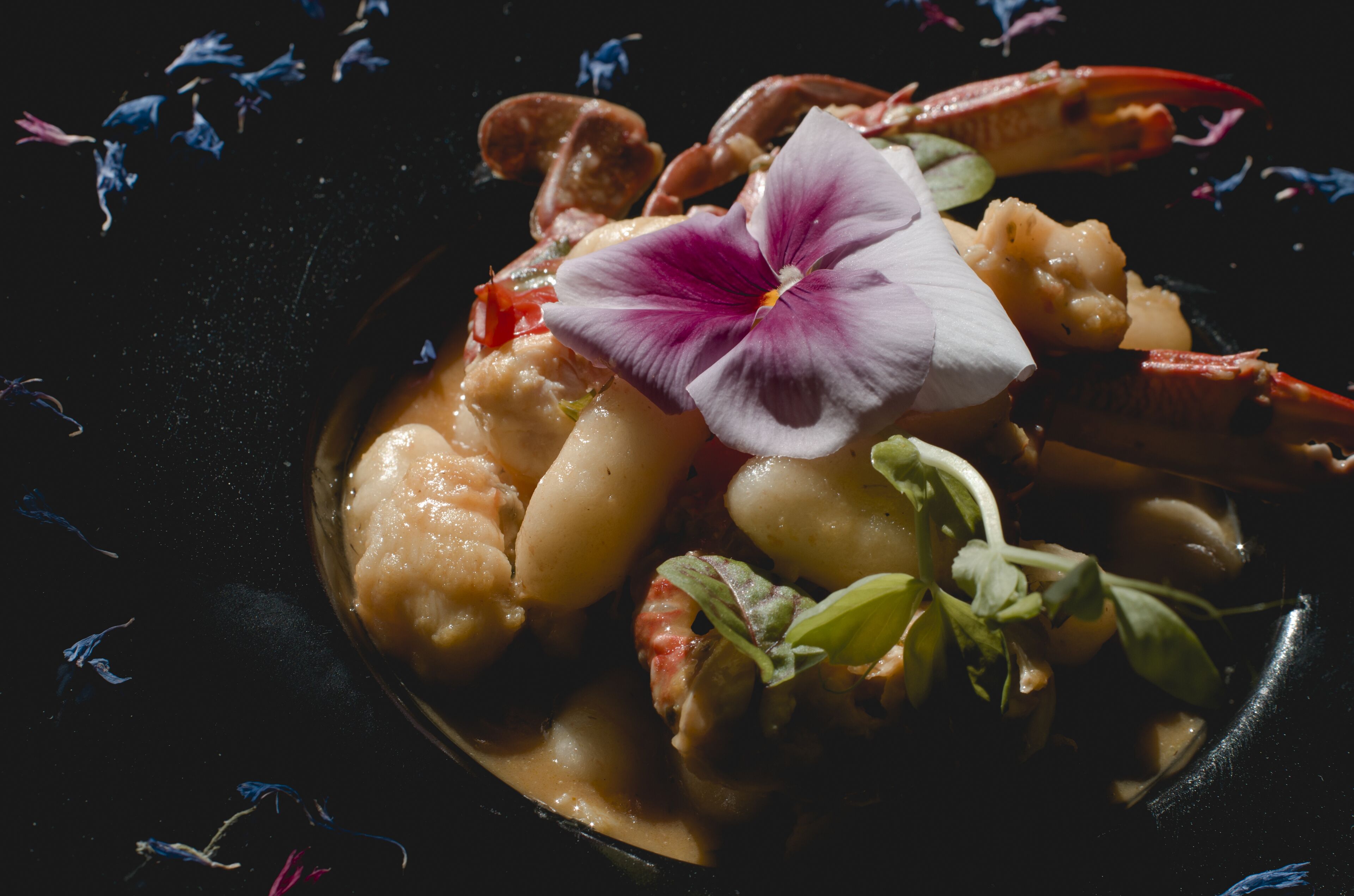 A dish with seafood and vegetables, garnished with a flower.