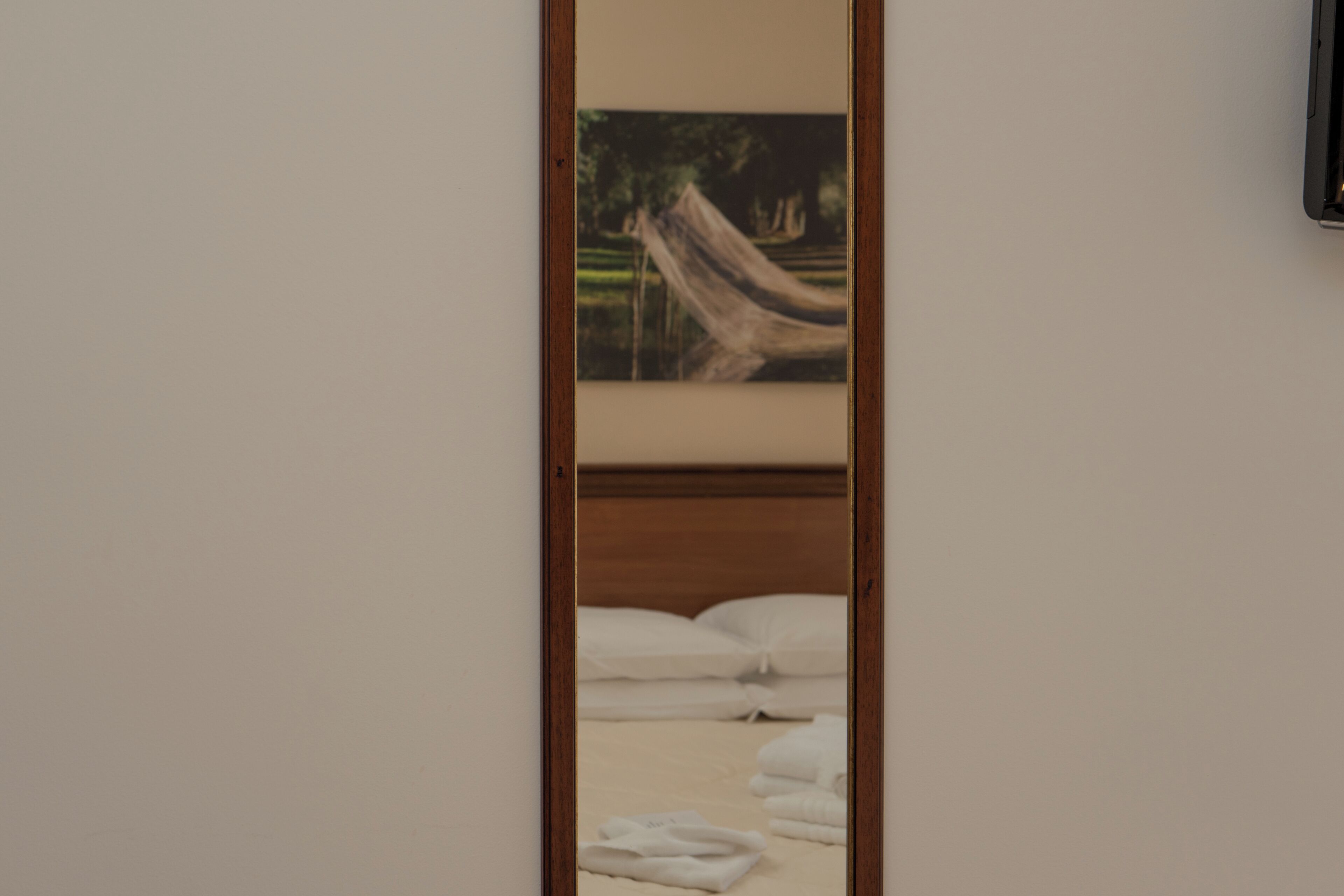 A bedroom with a bed, pillows, and a painting of a hammock.