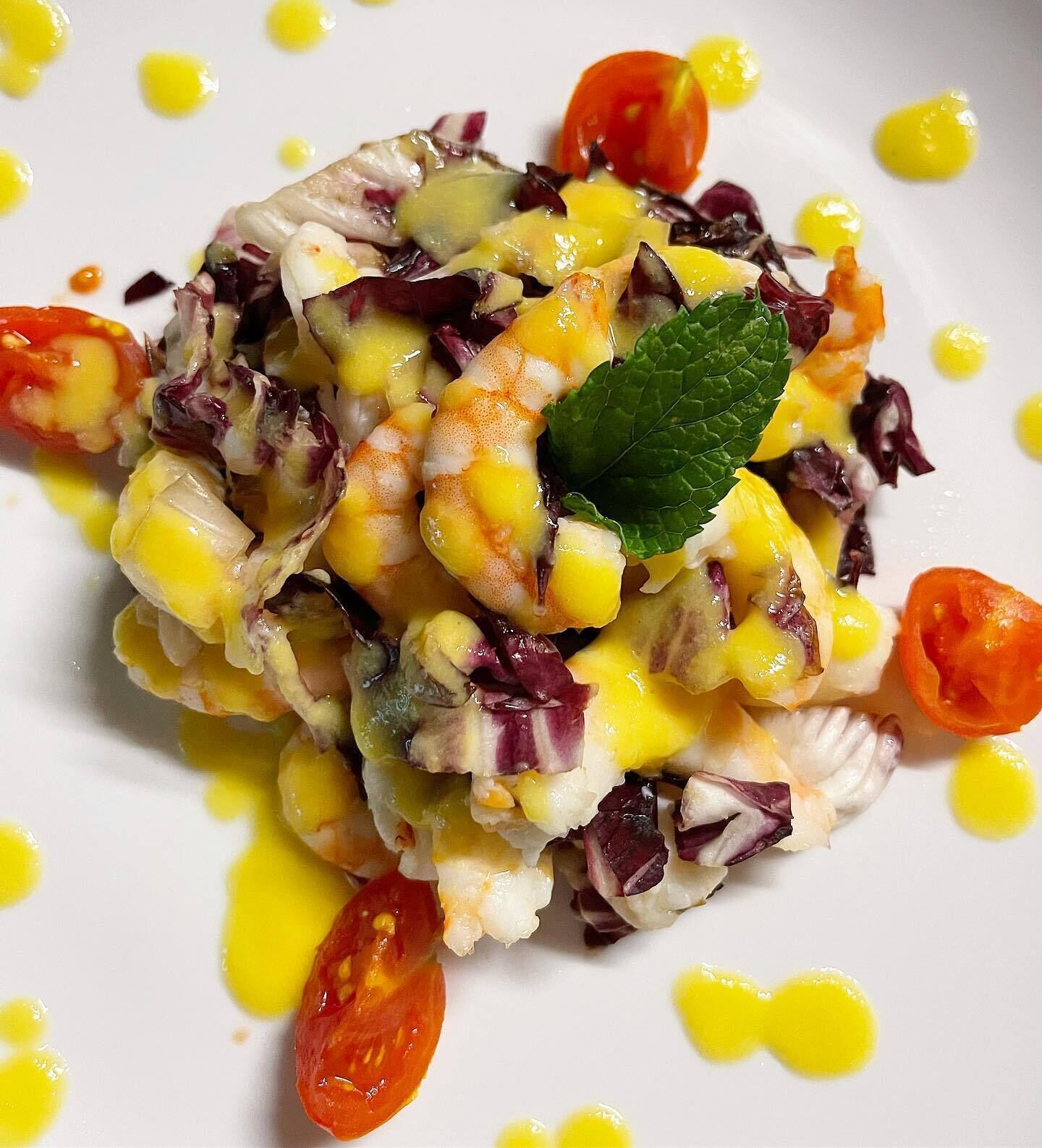 Un plat composé de crevettes, de chou rouge et de mangue, servi dans une assiette blanche.