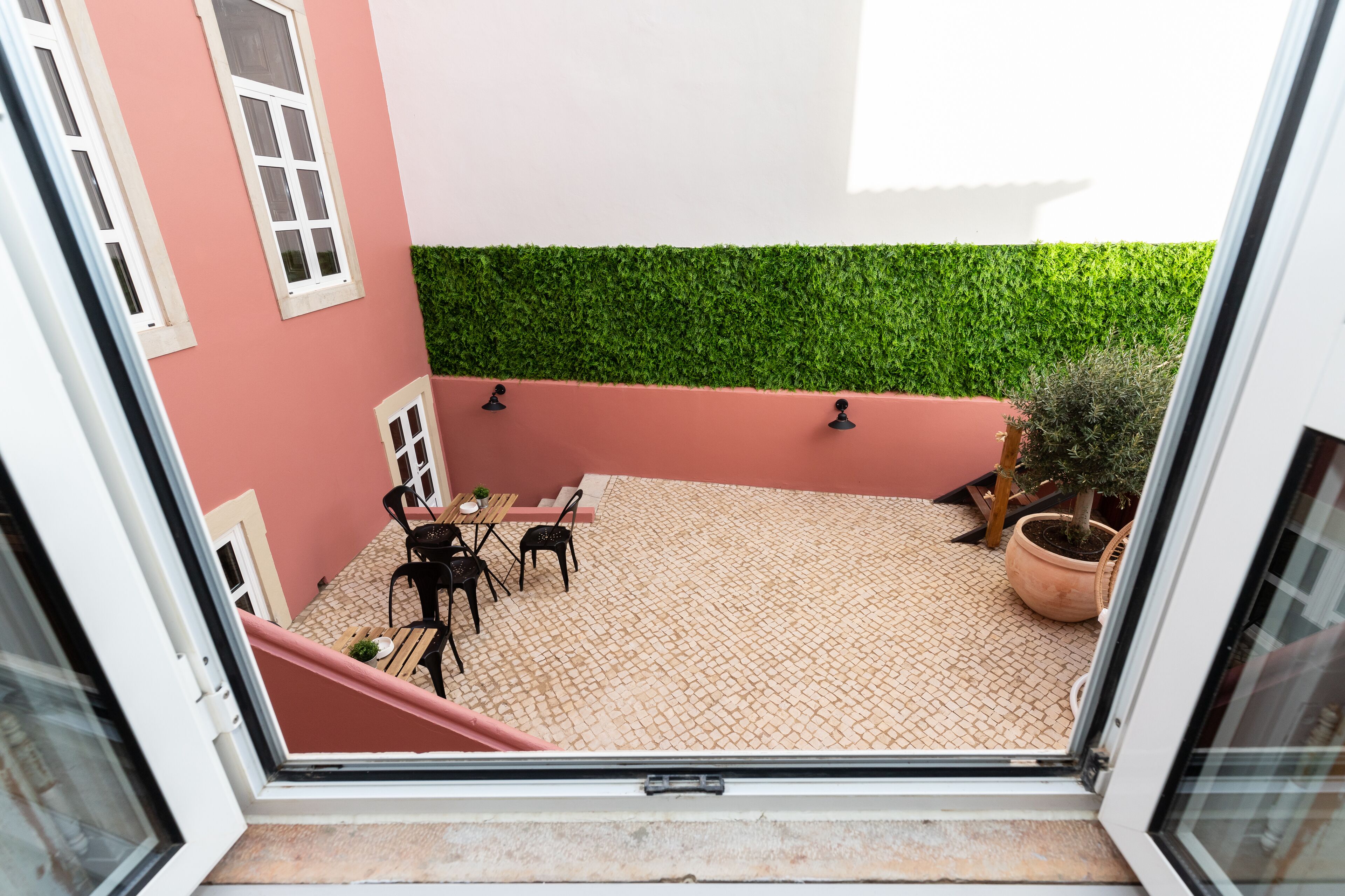 A courtyard with a tiled floor, a table with chairs, and a potted plant.