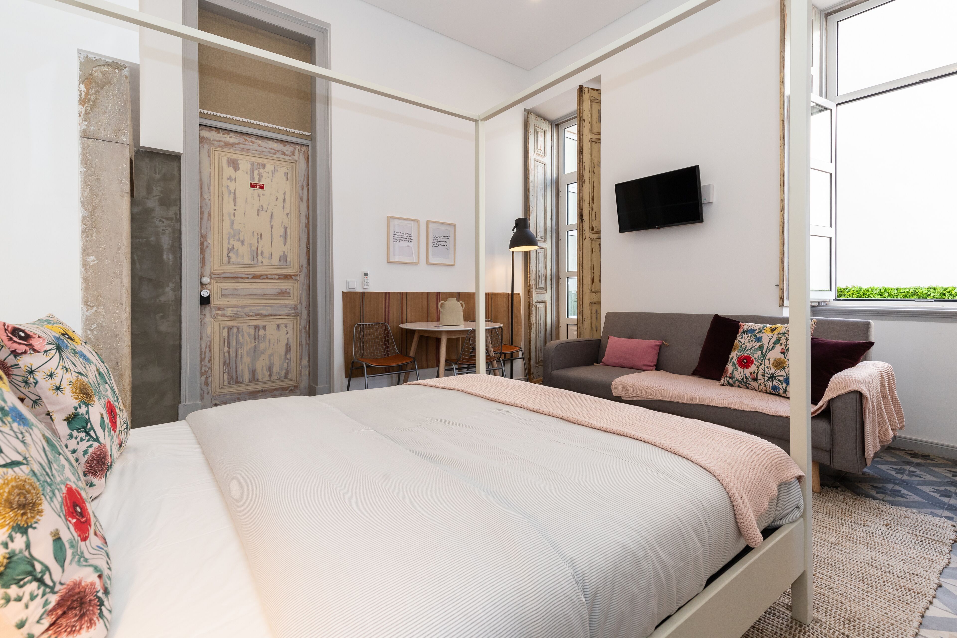 Una camera da letto moderna con un letto grande, un divano, un tavolino e una TV a parete.