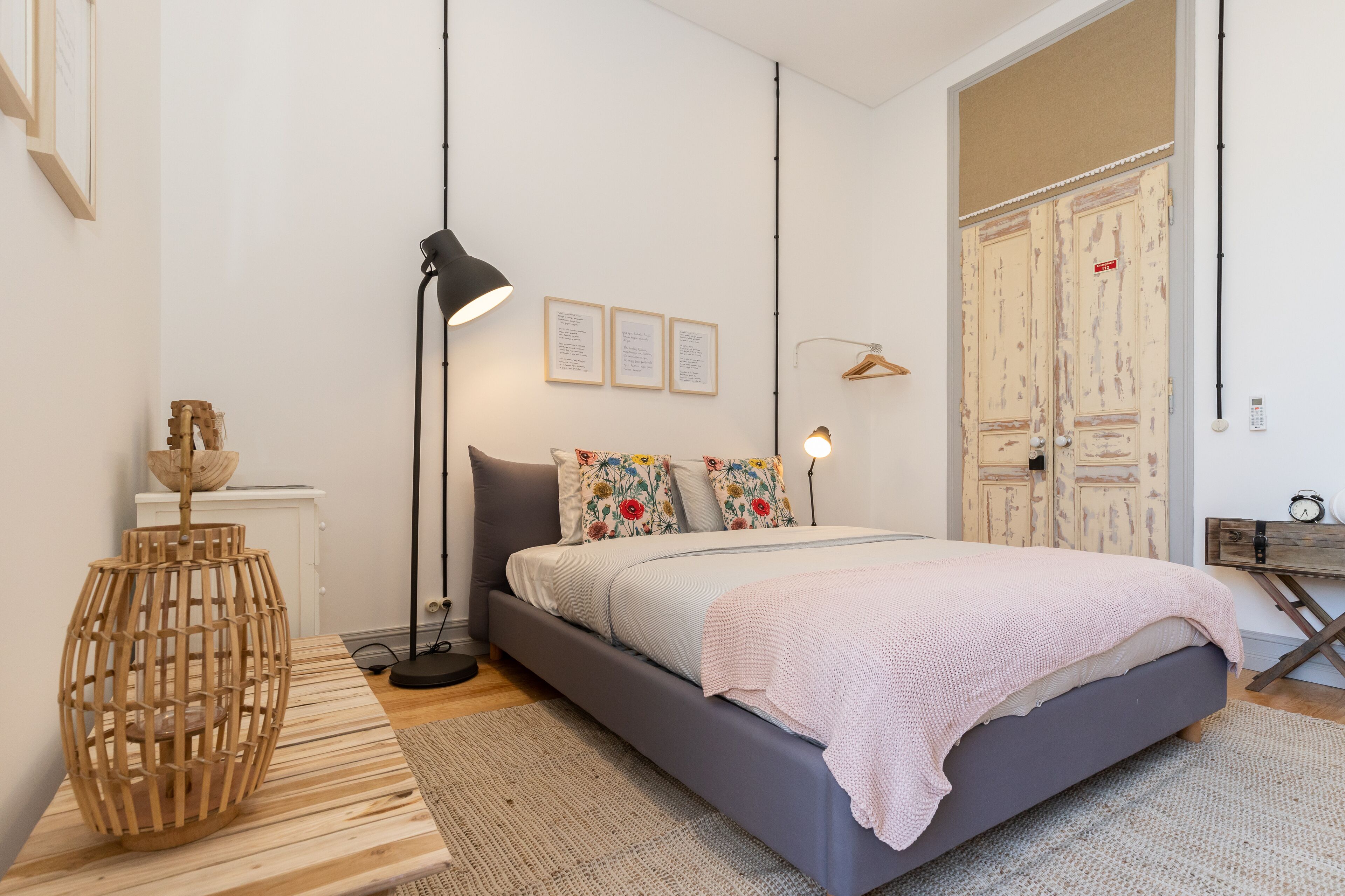 Une chambre à coucher avec un lit, des lampes de chevet, une table de chevet en bois et une étagère fixée au mur.