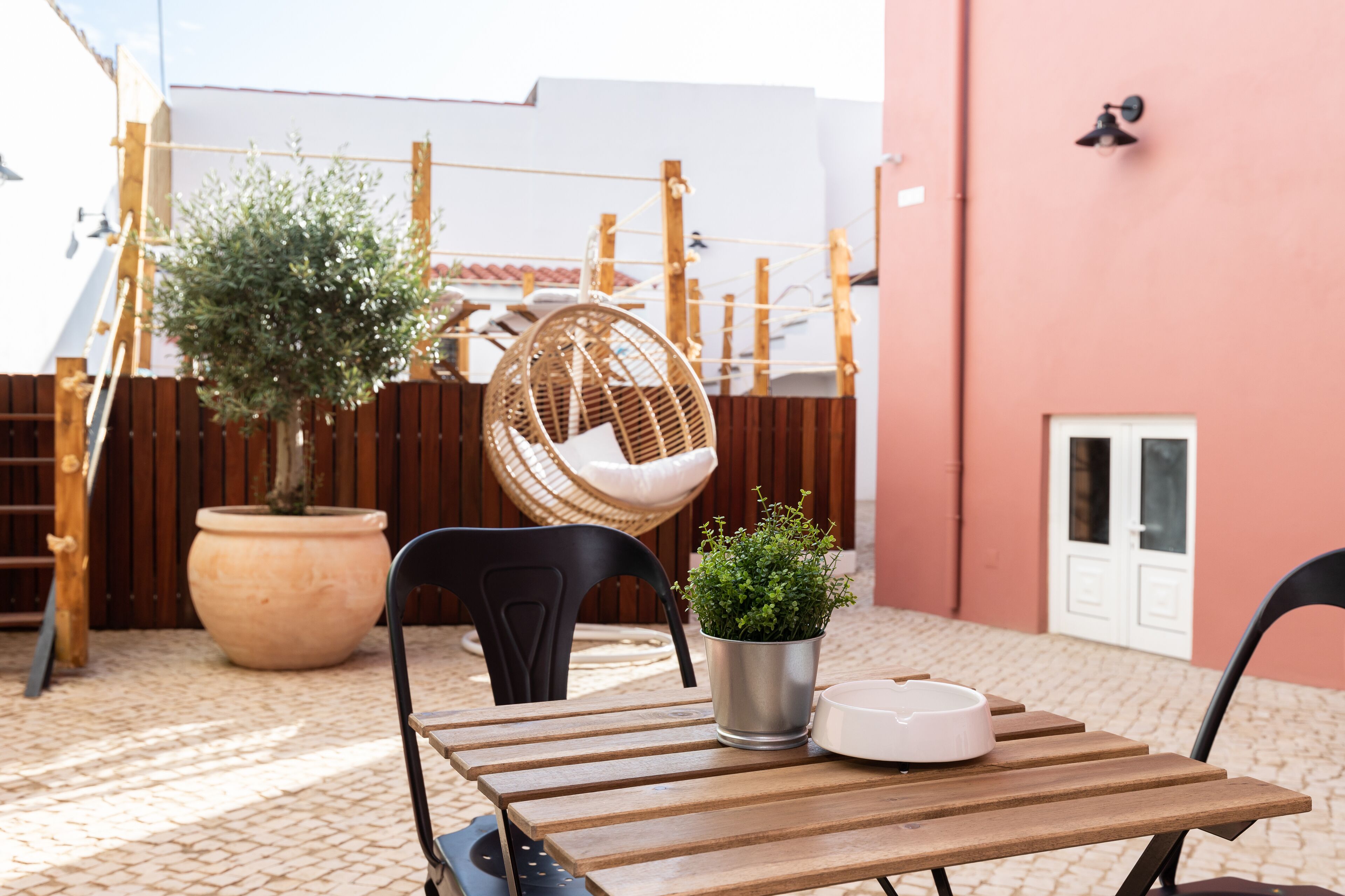 Une table en bois avec des chaises, une plante en pot et un bol blanc.